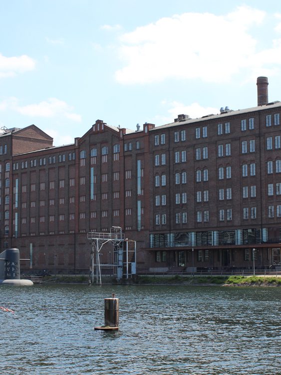 Rote Backsteinfassade eines historischen Gebäudes am Wasser. Küppersmühle, Innenhafen Duisburg