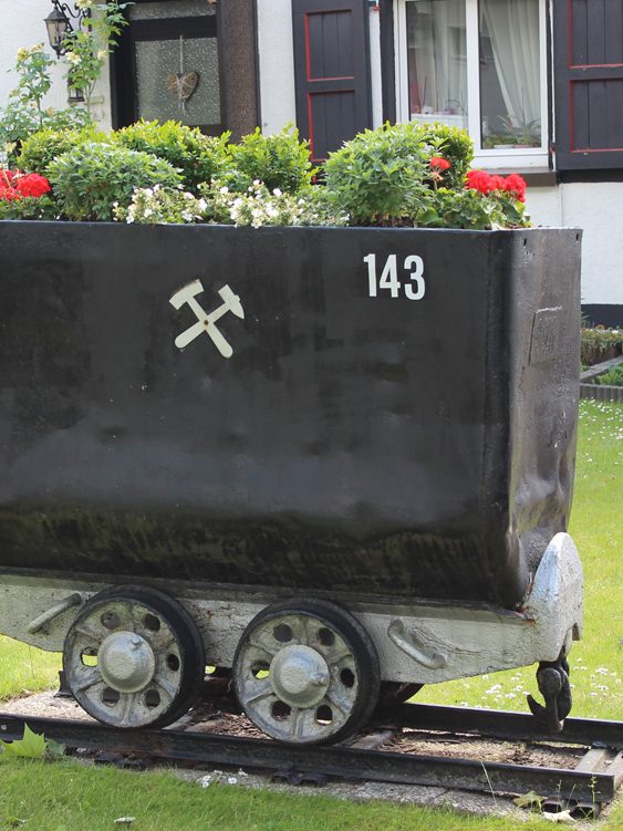 Förderwagen mit Pflanzen und Schlägel und Eisen als Dekor. Wunschtour durch's Ruhrgebiet